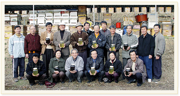 양봉장 사진과 꿀단지를 들고 있는 양봉회 회원들 단체사진